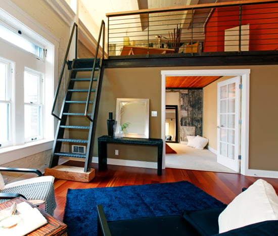 View of modern reconstructed living room with mezzanine area above bedroom. View of iron steep stairs