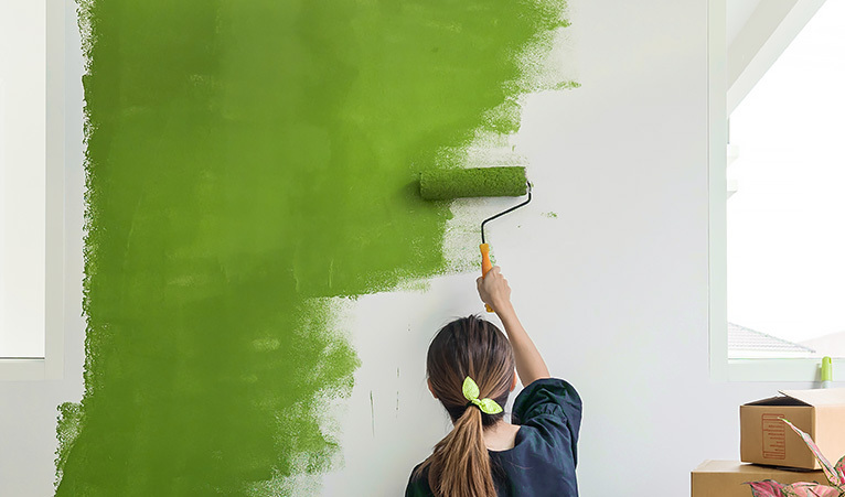 Girl painting a wall green