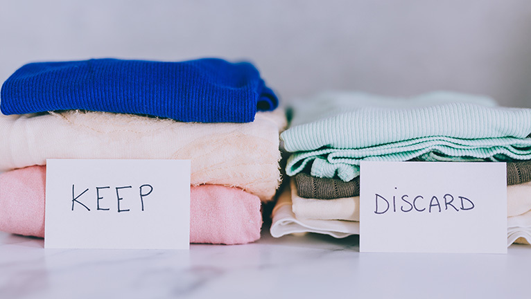Two piles of clothes marked keep and discard