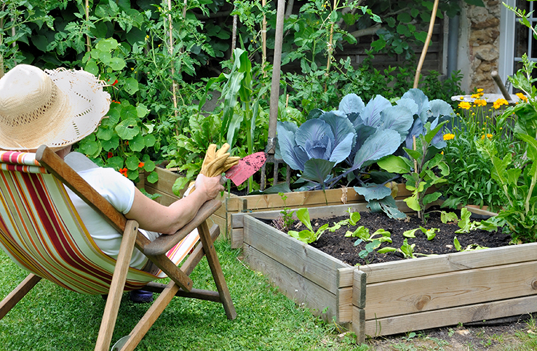 Lady relaxing by vegetable patch