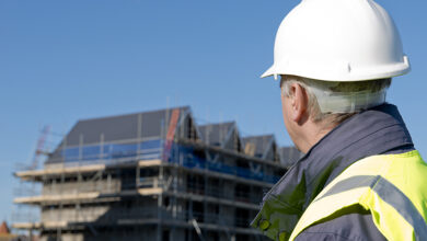 Man in hard hat looking at unfinished apartment block