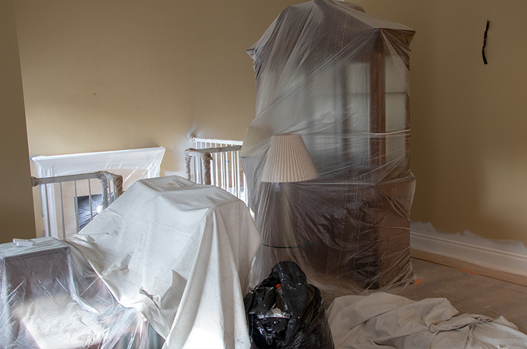 Room with furniture covered with dust sheets to prepare for home improvement work