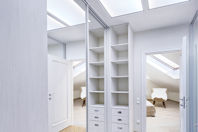Walk-in wardrobe loft conversion with built-in storage and a mirrored wardrobe