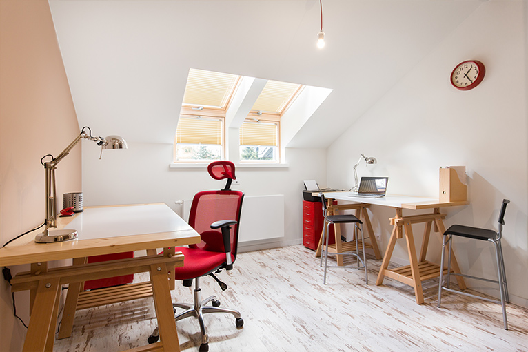 White office space with two desks and pops of the colour red from the desk chair, filing cabinets and hole punch