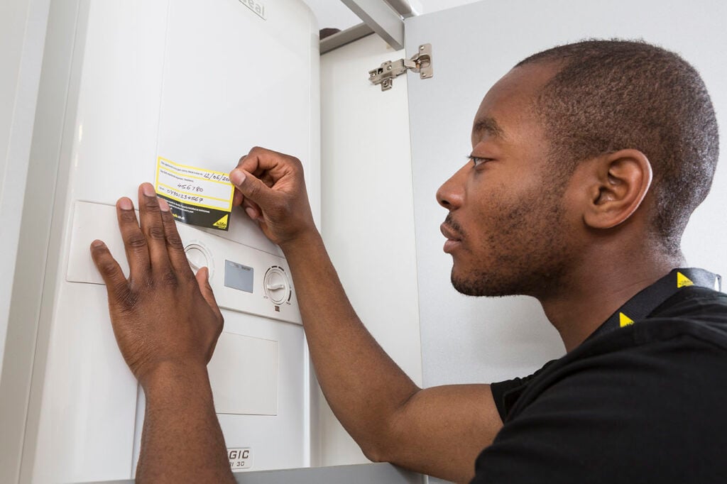 Gas Safe engineer attaching an annual service confirmation sticker to a boiler