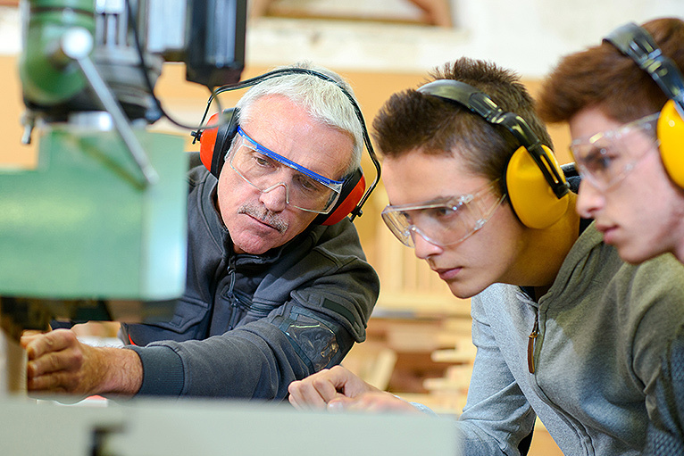 Tradesman teaching two apprentices 