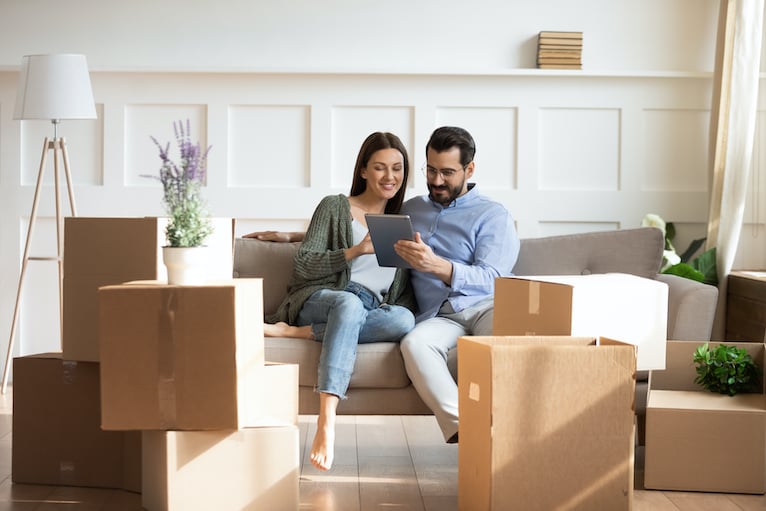 Couple looking at a tablet, surrounded by moving boxes