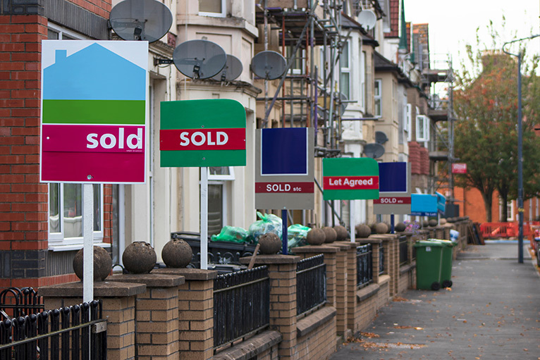 Estate agent signs outside a row of houses