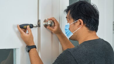Locksmith wearing a mask whilst fixing a door lock