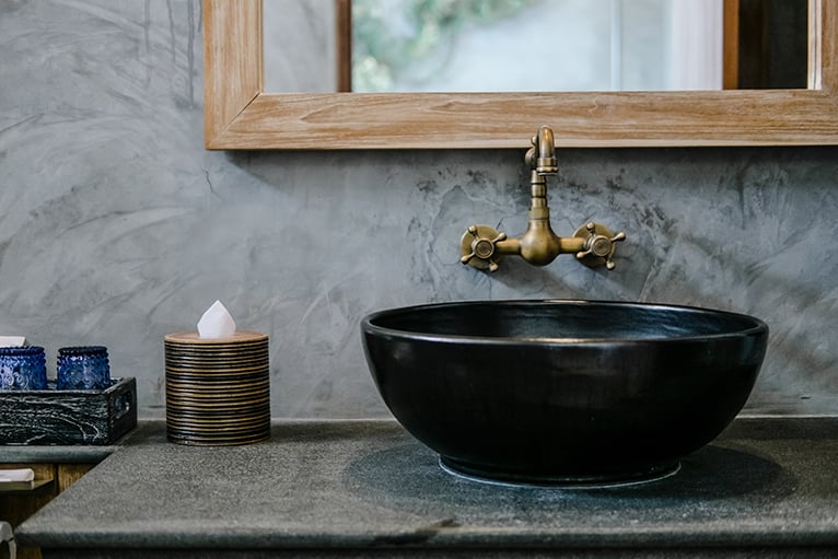 Rustic black sink with copper taps in a bathroom with grey decor