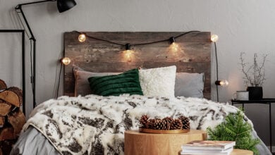 Bed with wooden headboard, fairylights, lamp and cosy blankets