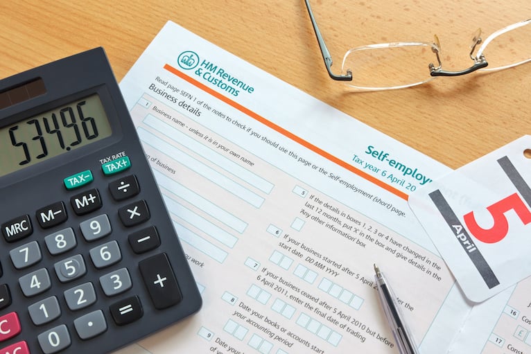 Self-assessment tax form, calculator and glasses on a table