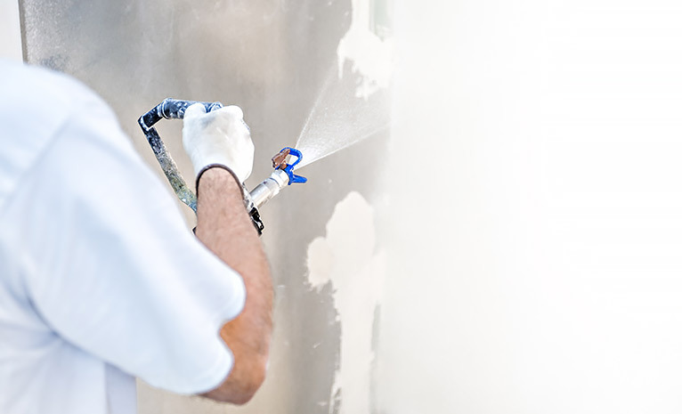 Painter spraying paint onto a wall