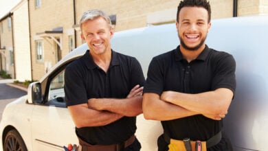 Tradespeople smiling and standing next to van