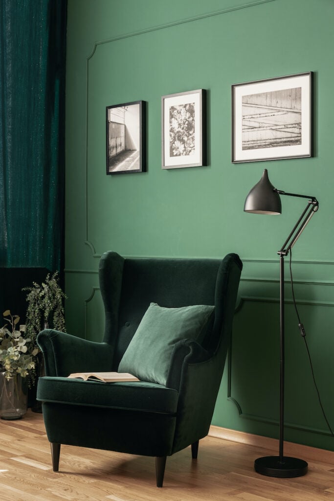 Home design: Dark green velvet chair in front of lighter green wall