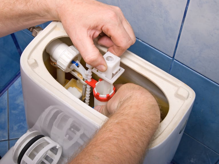 Plumbing problems: Person fixing issues inside toilet cistern