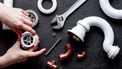 Hands surrounded by pipes, tools and other plumbing materials