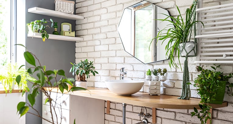 Bathroom with lots of plants and white brick wall