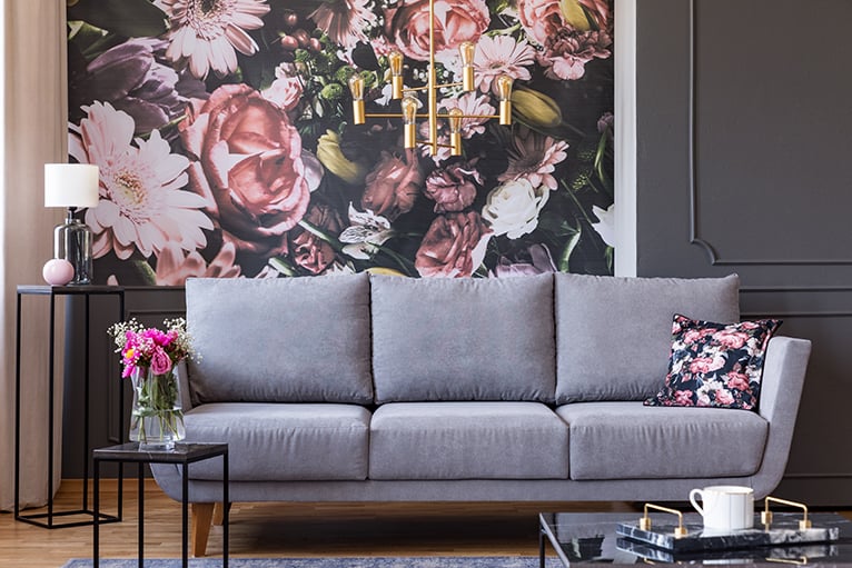 Grey sofa in front of floral feature wall