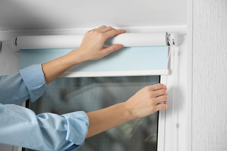 Person's hands installing blinds with baby blue lining