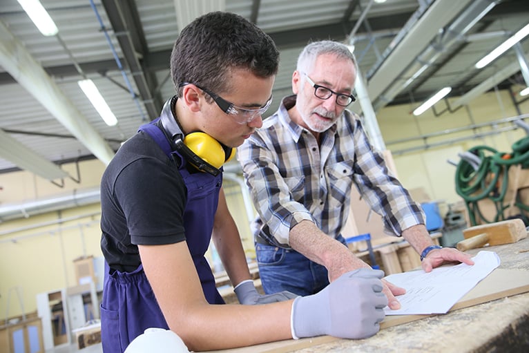 Carpenter teaching young apprentice