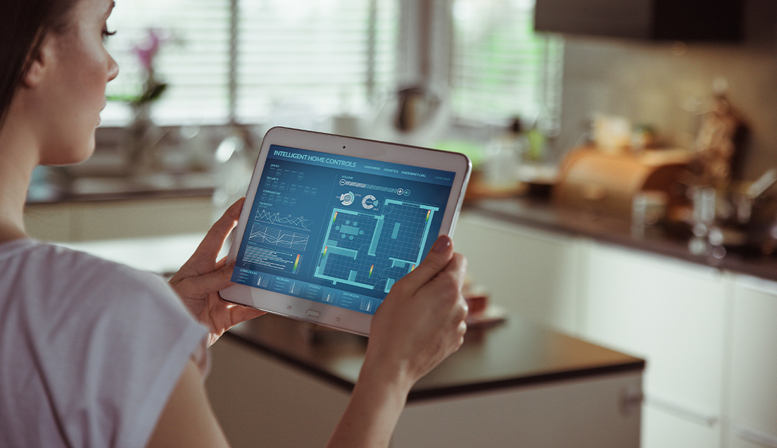 Woman using intelligent home controls software on a tablet to set the right temperature for each room.