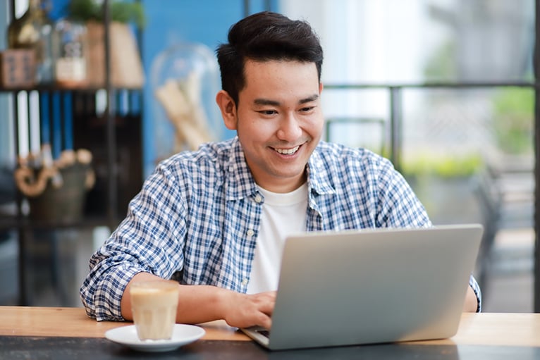 Money saving tips: Man using laptop in coffee shop