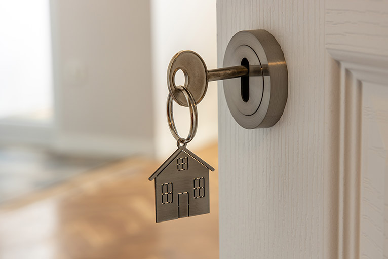 Key with house-shaped keyring in the door to a new home
