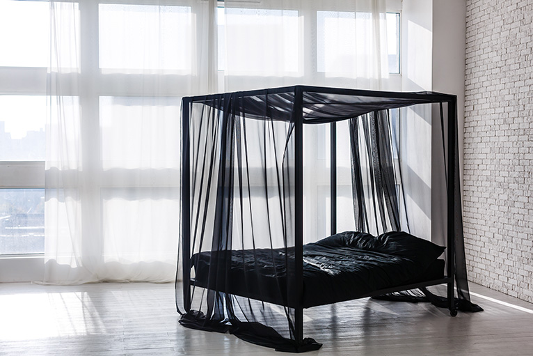 Black four poster bed with netting