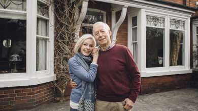 Happy elderly couple in front of house