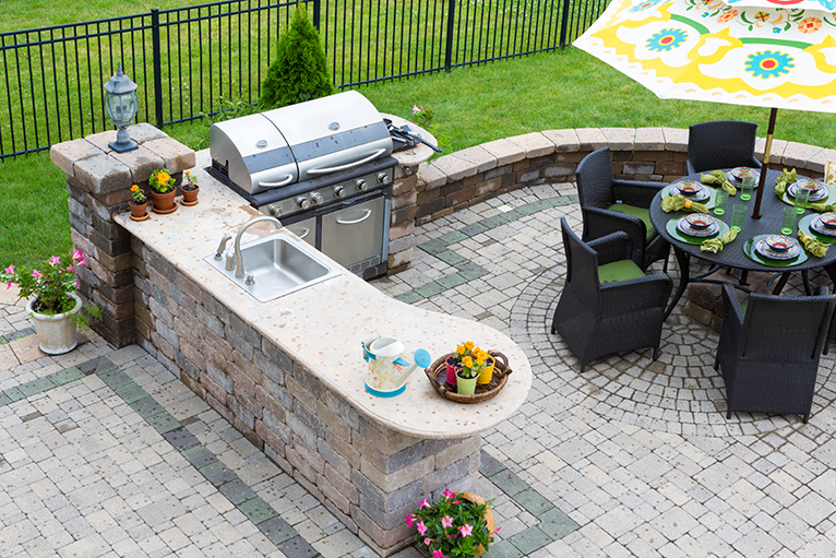 Garden with outdoor kitchen: sink, BBQ and seating area on paved patio