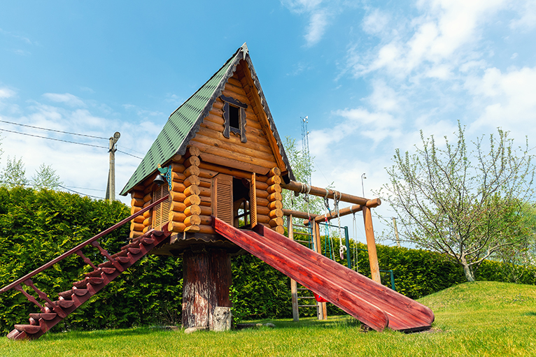 Wood treehouse with slide, swing and steps in large garden