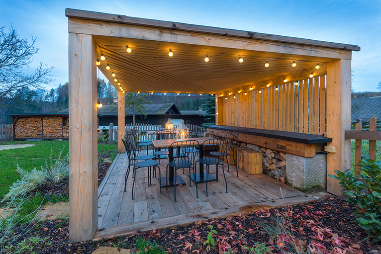 Large wood gazebo with lights on a summer night in all year round garden