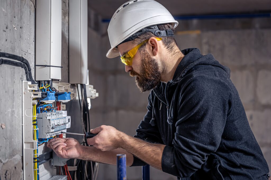 Picture of an electrician at work with a white hard hat on