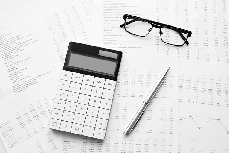 Calculator, pen, glasses and financial documents on table