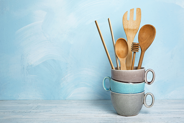Wooden utensils and mugs against light blue wall