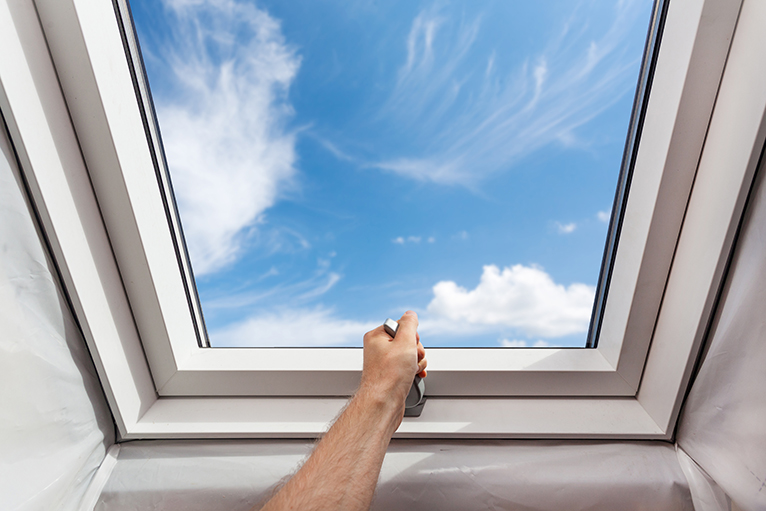 Person opening skylight window in attic