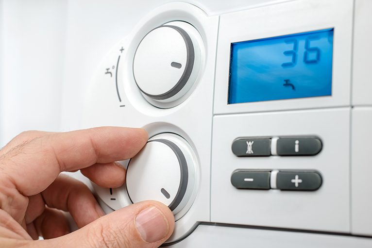 Energy efficiency home grants: Person adjusting heating control panel
