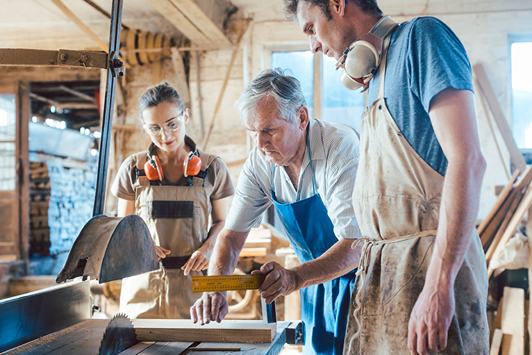 Master carpenter teaching apprentices during trades apprenticeship