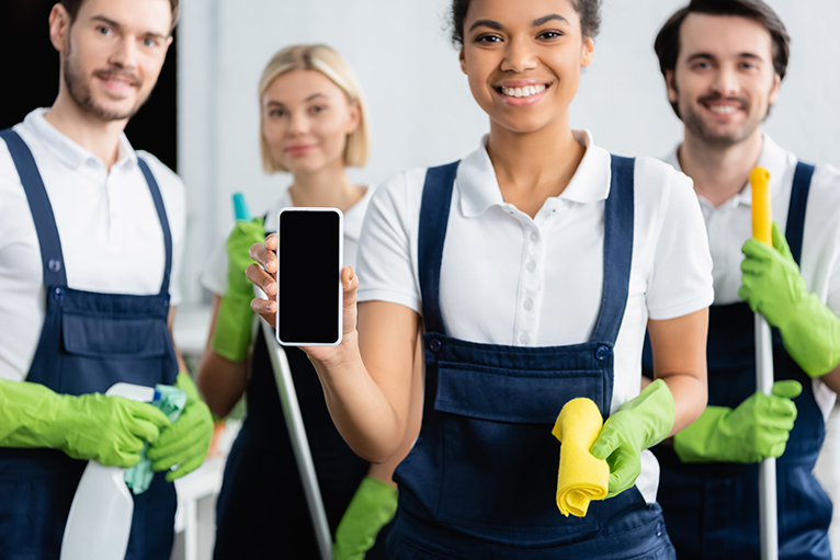 Smiling cleaner holding smartphone