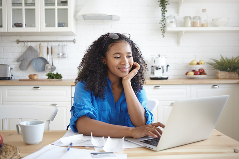 Person looking happily at laptop and bills