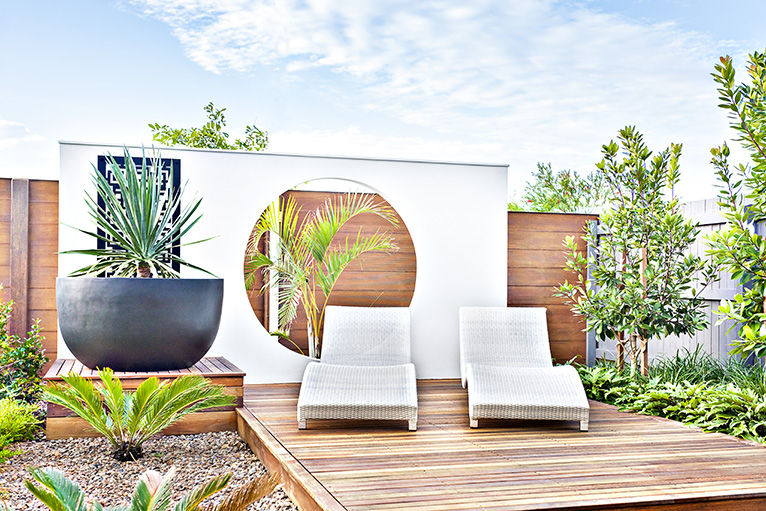Love Island garden inspiration: Outdoor seating area with wooden patio, large plants and sun loungers
