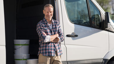 Smiling tradesperson standing in front of work van