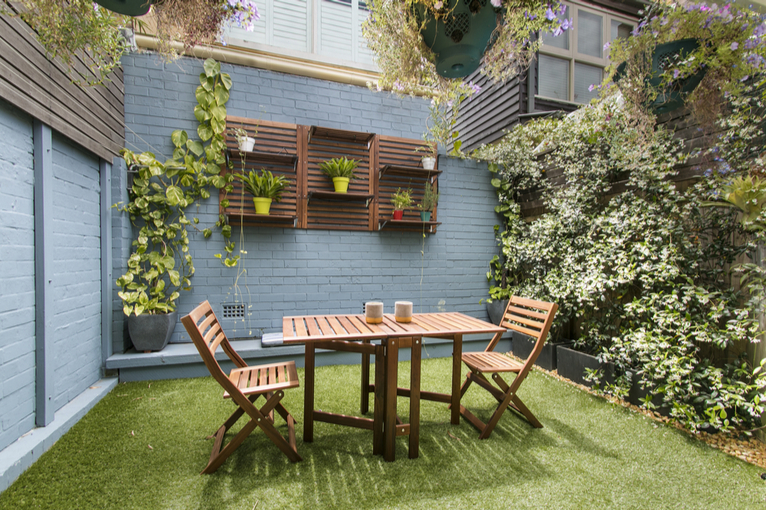 Awkward shaped small city garden with outdoor dining set, living wall and astroturf