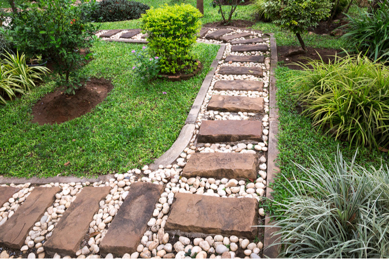 Garden path with stones and plants in edging