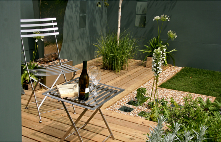 L shaped patio with metal dining set and grassy plants