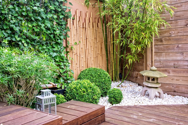 Multi-level garden with bamboo, stone garden ornaments and tall plants