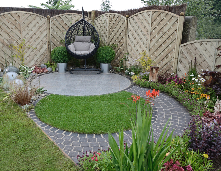 Awkward shaped small garden with egg chair, circular paving and small landscaped lawn