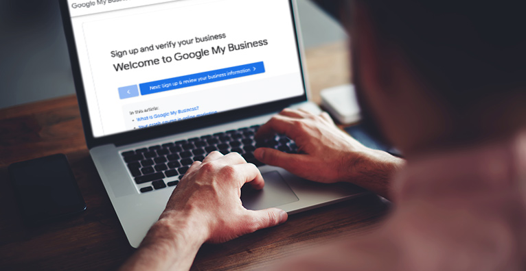 Man sat in front of open laptop with a screen that reads: 'Welcome to Google My Business'. 