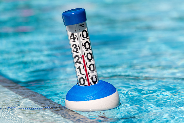 Close up of a thermometer, floating in a swimming pool. 
